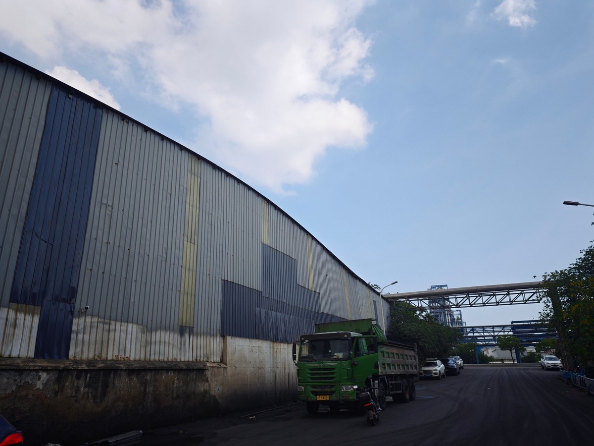 祥荣再生资源弧形屋顶厂房外景、场内自卸车与厂区输送廊道