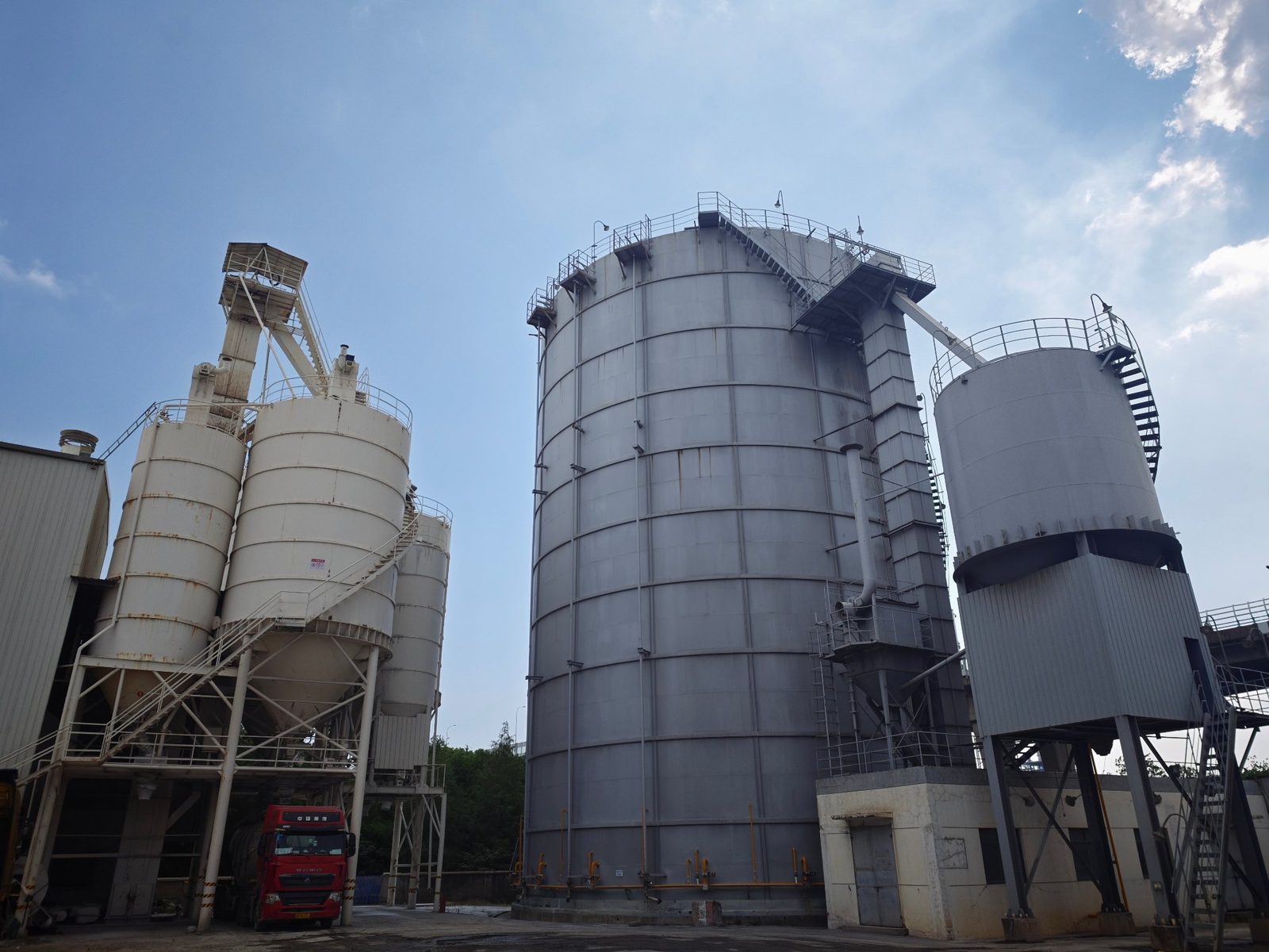 祥荣再生资源筒仓群侧面视角，可见检修爬梯、输送廊道与厂区硬化地面
